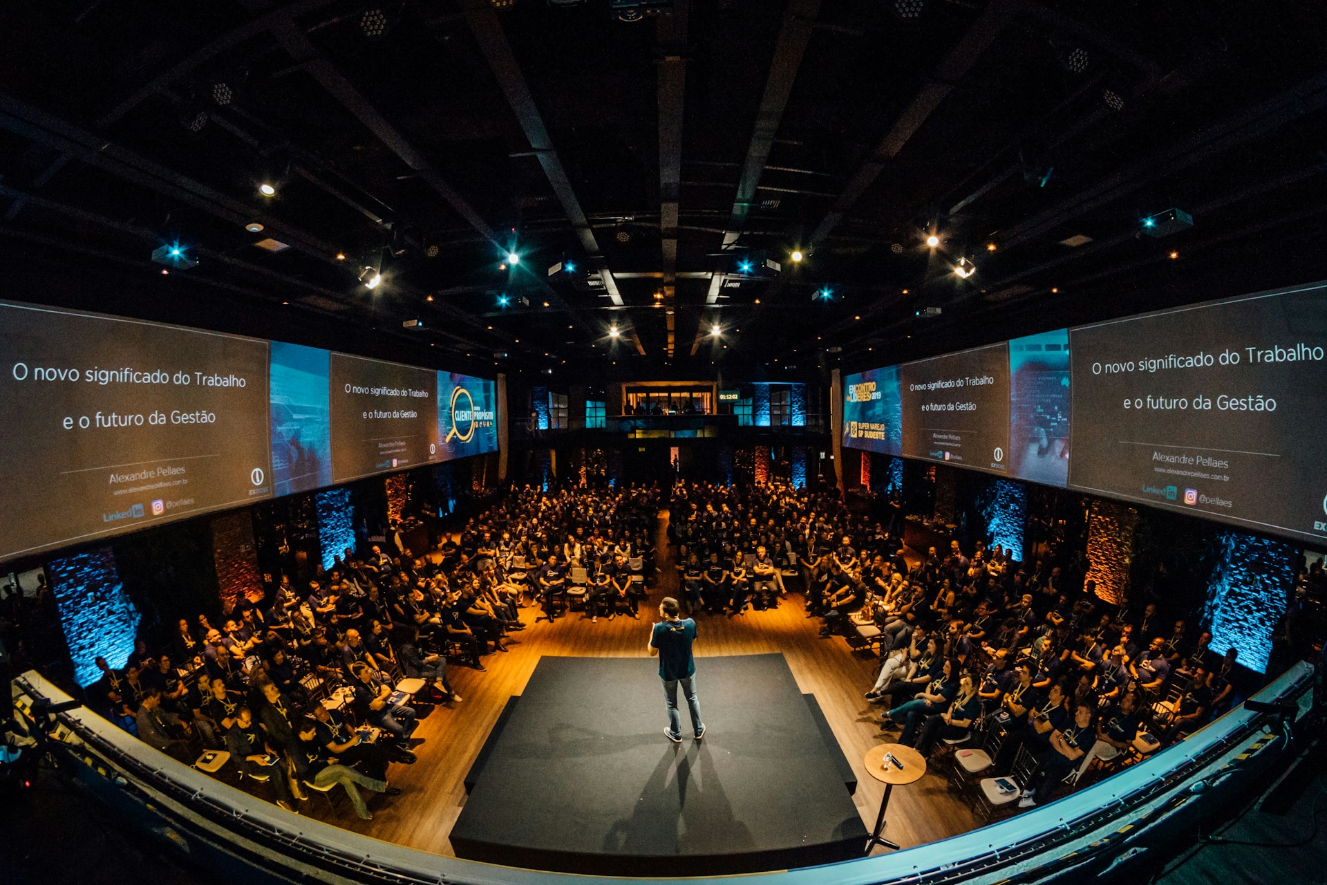 Corporate general session — keynote speaker on stage, large LED walls, moody event lighting